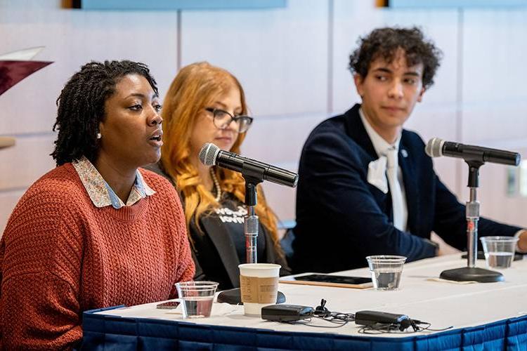 A panel of diverse, young professionals speak at an event